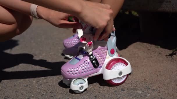 クローズアップママは夏に公園で娘の子供にインラインスケートローラーを置く ファミリーレジャーアウトドアスポーツ活動ゲーム — ストック動画