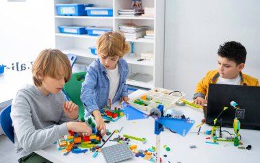 Robot programlama dersi. Çocuklar robot yapıp kodluyorlar. İnşaat blokları, dizüstü bilgisayar ve uzaktan kumandalı joystick kullanarak STEM eğitimi. Okul çocukları için teknolojik eğitim gelişimi