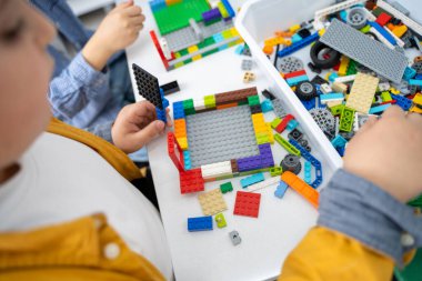 Robot programlama dersi. Çocuklar robot yapıp kodluyorlar. İnşaat blokları, dizüstü bilgisayar ve uzaktan kumandalı joystick kullanarak STEM eğitimi. Okul çocukları için teknolojik eğitim gelişimi