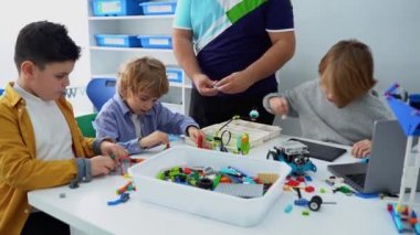 Robot programlama dersi. Çocuklar robot yapıp kodluyorlar. İnşaat blokları, dizüstü bilgisayar tableti, uzaktan kumandalı joystick kullanarak STEM eğitimi. Okul çocukları için teknolojik eğitim gelişimi