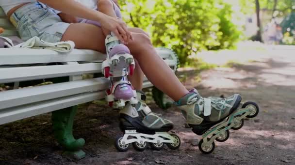 一緒に公園でインラインローラーをスケートした後 母と娘がベンチに座って閉じます 家族レジャースポーツ活動週末 負のスペースをコピー — ストック動画