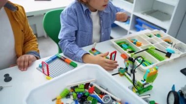 Robot programlama dersi. Çocuklar robot yapıp kodluyorlar. İnşaat blokları, dizüstü bilgisayar tableti, uzaktan kumandalı joystick kullanarak STEM eğitimi. Okul çocukları için teknolojik eğitim gelişimi