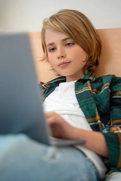 Smart caucasian middle School child boy using laptop. Child typing on the keyboard. Play video game.Online tutor teaching digital class, web lesson on computer at home. Virtual education. E-education