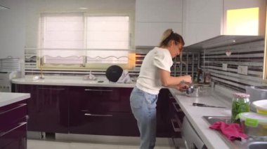 Orta Doğulu sevimli, mutlu bir kadın mutfakta yemek pişirirken dans edip şarkı söylüyor. evcilleştirilmiş yaşam tarzı rutini.