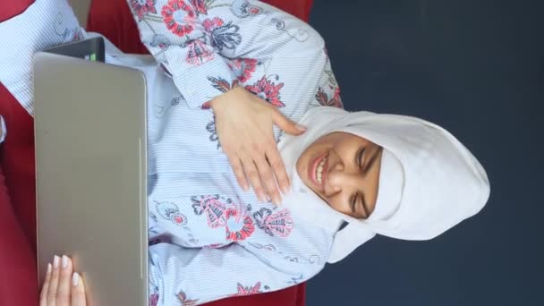 美しい幸せなイスラム教徒のアラビア人女性を使用してノートパソコンのリモートワークホームオフィス屋内 女性デバイス教育に取り組むヒジャーブ州オンラインショッピング ソーシャルメディア垂直 — ストック動画