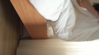 Yataktan cama dayanan güzel bir genç kızın yakın plan kadın bacakları. Hafif arka plan, sabah uyanır. Beyaz yatak güzel kadın ayak parmakları. Yere yatın. parke ya da kaplama