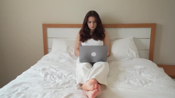 十几岁的女孩在家里的床上用笔记本电脑 年轻妇女学习 用小玩意工作 远距离学习 自由职业者 远程工作 学生会话 在线教育 — 图库视频影像