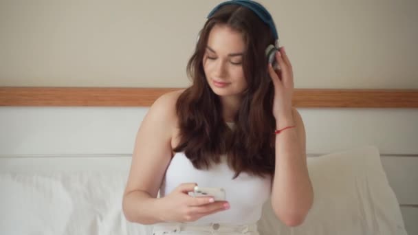 Приваблива Молода Жінка Слухаючи Музику Навушниках Використовує Смартфон Вдома Посмішка — стокове відео
