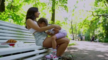 Anne ve kızı halka açık parkta paten kaydıktan sonra yedek kulübesinde oynuyorlar. Aile eğlencesi spor etkinliği hafta sonu.
