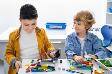 Robot programlama dersi. Çocuklar robot yapıp kodluyorlar. İnşaat blokları, dizüstü bilgisayar ve uzaktan kumandalı joystick kullanarak STEM eğitimi. Okul çocukları için teknolojik eğitim gelişimi