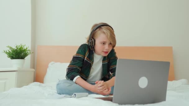 Мальчик Подросток Использующий Ноутбук Наушники Ребенок Ищет Онлайн Видеоурок Постели — стоковое видео