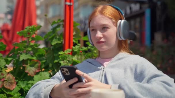 Tiener Meisje Koptelefoon Met Behulp Van Smartphone Cafe Outdoor Drankje — Stockvideo