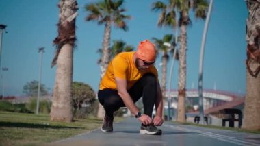 Spor giyimli koşucu, hafta sonu koşu bandında koşmadan önce ayakkabı bağcıklarını bağlar. Orta yaşlı yetişkinler için sağlıklı yaşam tarzı, kilo vermek, yağ yakmak, spor yapmak.