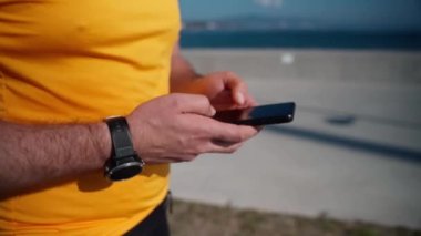 Spor faaliyetlerini yaptıktan sonra akıllı telefonu kullanarak koşan adamı kapat. Mafya uygulaması, takip cihazı, hız, kalp atışı. Sportif cep telefonu uygulamaları kullanarak idmandan sonra koşan yetişkin