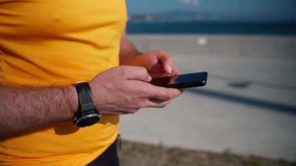 スポーツ活動を実行した後 スマートフォンを使用してジョギング男を閉じます モブアプリトラッカースピードハートビート 携帯電話のスポーツアプリを使用してトレーニング後のランナー大人 — ストック動画