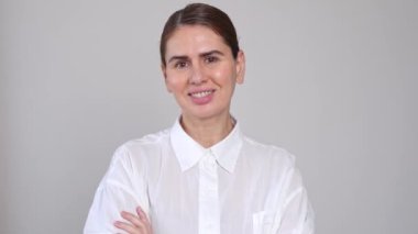 Gri arkaplandan kameraya bakan güzel bir iş kadını. Mutlu gülüşler kendine güvenen 40 yaşındaki beyaz kadın profesyonel. Sofistike esmer kadın reklamının portresi.