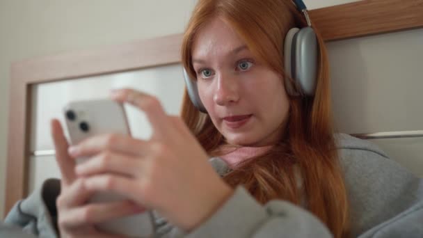 Genç Kız Kulaklığı Evde Yatakta Akıllı Telefon Kullanıyor Genç Kadın — Stok video