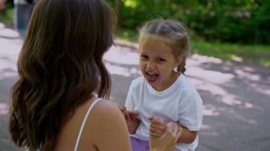 Anne ve kızı halka açık parkta paten kaydıktan sonra yedek kulübesinde oynuyorlar. Aile eğlencesi spor etkinliği hafta sonu.