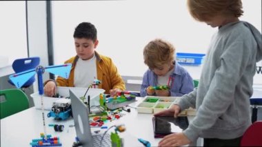 Robot programlama dersi. Çocuklar robot yapıp kodluyorlar. İnşaat blokları, dizüstü bilgisayar tableti, uzaktan kumandalı joystick kullanarak STEM eğitimi. Okul çocukları için teknolojik eğitim gelişimi