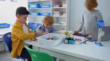 Robot programlama dersi. Çocuklar robot yapıp kodluyorlar. İnşaat blokları, dizüstü bilgisayar tableti, uzaktan kumandalı joystick kullanarak STEM eğitimi. Okul çocukları için teknolojik eğitim gelişimi