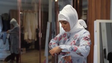 Evde başörtüsü takan orta yaşlı Müslüman kadın portresi başörtüsü takıyor. Aynaya bakıyor. Başörtüsü ile kaplanmış neşeli bir kadın yüzü. Gündelik İslamcı kız.