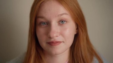 Açık arkaplanda kızıl saçlı, güzel, yetişkin bir kadının portresi. Olumlu gülümse. Yaklaş.