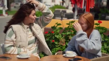 Kahve molası veren iki genç kız yaz mevsiminde açık havada güneşli hava kahvesi içiyorlar. Genç kadınlar konuşuyor, dedikodu yapıyor, sohbet ediyor, eğleniyor.. 