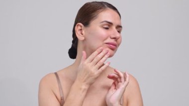 Orta Yaşlı Kadın Yüze Dokunan Beyaz Arkaplan. 40 yaşındaki kadın kameraya bakıp gülümsüyor. Doğal güzelliğinin, kendine olan saygısının ve sağlığının tadını çıkarma kavramı. Doğal Kozmetik Cilt