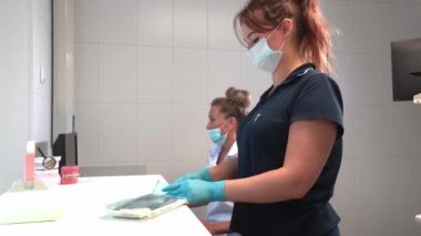 Kadın doktor ve asistan klinikte çalışıyor. İlaç evrakları, hastalar, hastalık geçmişi sağlık çalışanları rutini