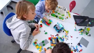 Robot programlama dersi. Çocuklar robot yapıp kodluyorlar. İnşaat blokları, dizüstü bilgisayar tableti, uzaktan kumandalı joystick kullanarak STEM eğitimi. Okul çocukları için teknolojik eğitim gelişimi