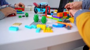 Robot programlama dersi. Çocuklar robot yapıp kodluyorlar. İnşaat blokları, dizüstü bilgisayar tableti, uzaktan kumandalı joystick kullanarak STEM eğitimi. Okul çocukları için teknolojik eğitim gelişimi