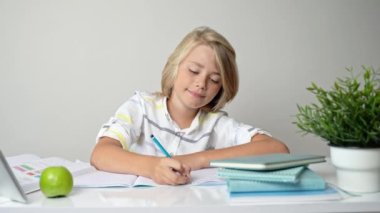Orta okulda gülümseyen öğrenci masada oturuyor, kitap ödevi ve tablet yazıyor eve, okula geri dönüyor. Çocukluk, çocuklar için eğitim