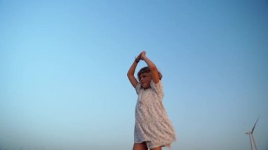 Rahat çocuk, temiz hava soluyor. Yazın alacakaranlıkta mavi gökyüzünün üzerinde kollarını kaldırıyor. Hayal, özgürlük ve seyahat konsepti.