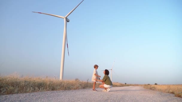快乐的母亲小女孩在风车场跳舞旋转转身 妈妈和女儿在一起享受时光 在更环保 可持续和高效的能源中呼吸洁净的空气 — 图库视频影像