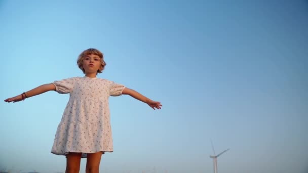 在夏天的黄昏时分 松驰的小女孩在蓝天落日的余晖下呼吸着新鲜空气 张开双臂 自由和旅行概念 — 图库视频影像