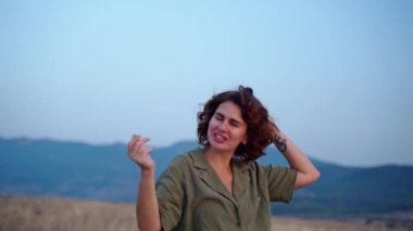 Rahat bir kadın, yaz mevsiminde dağlarda gün batımında kollarını kaldırarak temiz hava soluyor. Hayal kurmak, özgürlük ve seyahat kavramı. Kadın ruhsal sağlığı.