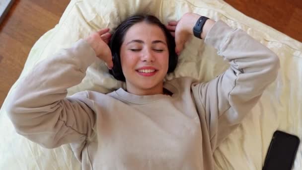 Młoda Nastolatka Kobieta Słuchawkami Sypialni Leżącej Uśmiechnięta Słuchać Podcastu Radiowego — Wideo stockowe