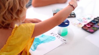 Resim fırçası akvaryumunda suluboya ile çocuk boyası. Bir grup ilkokul öğrencisi öğretmenlerinin nasıl resim çizip boyayacağını öğreniyor..