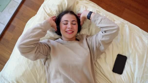 Kulaklıklı Yalan Söyleyen Gülümseyen Bir Genç Kız Radyo Yayını Dinliyor — Stok video
