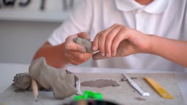 Sanat okulundaki genç çocuk, Sanat sınıfındaki Clay Sculpt. Ortaokul çocuğu öğretmenin yardımıyla yaratmayı öğreniyor.