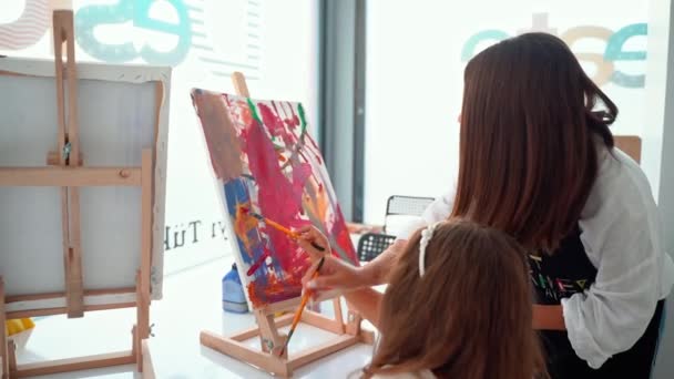 美术学校的教师帮助孩子们学习绘画 妇女教孩子创作和使用丙烯酸涂料 小学生小组学习如何绘画和彩色的帮助他们 — 图库视频影像