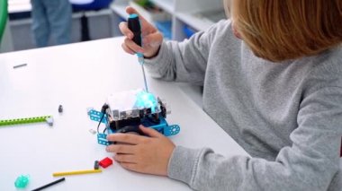 Robot programlama dersi. Çocuk, Mbot tornavida ve kod robotu yapıyor. İnşaat blokları, dizüstü bilgisayar tableti, uzaktan kumandalı joystick kullanarak STEM eğitimi. Teknoloji eğitimsel gelişimi