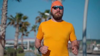 Orta yaşlı bir adam güneşli bir sabah hazırlık maratonunda koşuyor. Orta yaşlı yetişkinler için sağlıklı yaşam tarzı, kilo vermek, yağ yakmak, spor yapmak.