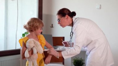 Çocuk aşısı çocuk hastanesi kliniğinde. Şırıngayla doktor enjeksiyonu. Çocuğun sağlıklı yaşam tarzı ve bakımı hakkında olumlu düşünceler.