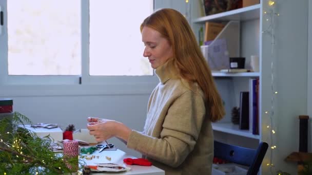 ジンジャーの赤毛の女性は新年の木のためのクリスマスの装飾のおもちゃを作成します クラフトメモリの伝統 休日の家族は 居心地の良い家のために手作りしました サイドビュー — ストック動画