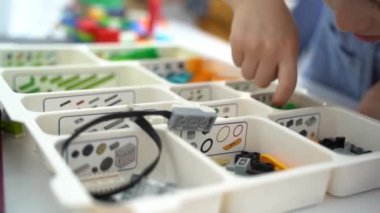 Robot programlama dersi. Çocuklar robot yapıp kodluyorlar. İnşaat blokları, dizüstü bilgisayar tableti, uzaktan kumandalı joystick kullanarak STEM eğitimi. Okul çocukları için teknolojik eğitim gelişimi