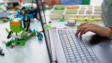 Okul çocukları robot yapıp kodluyorlar. Dizüstü bilgisayar ve uzaktan kumandalı joystick kullanarak BTMM eğitimi. Okul çocukları için teknolojik eğitim gelişimi. Öğrenciler bilgisayar kullanarak robotik arabalar yapıyorlar.