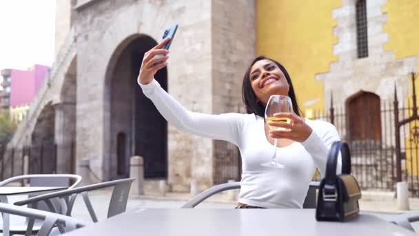 カフェのラテンアメリカの若い女性は スマートフォンを使用してワインを飲んで セルフィーを作ります オーダーを待っています ハッピーライフスタイル 日常生活の技術 ビッグシティでのランチ — ストック動画