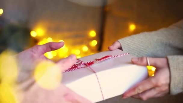 特写镜头中的女性将圣诞礼物送给男性的手放在轻巧的花环上 甜蜜的时刻亲密的 亲切的情侣们 以惊喜的礼物互相祝贺对方 — 图库视频影像