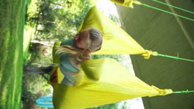 Kadın yoga havası parktaki hamakta ters dönmüş asanalar. Spor eğitimi temiz hava. Orta yaşlı kadın yetişkinler için esneme, meditasyon ve zihinsel refah. Sağlık bakımı.